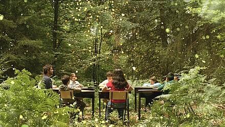 Bild zum Film: Kinder sitzen im Wald an einem Tisch