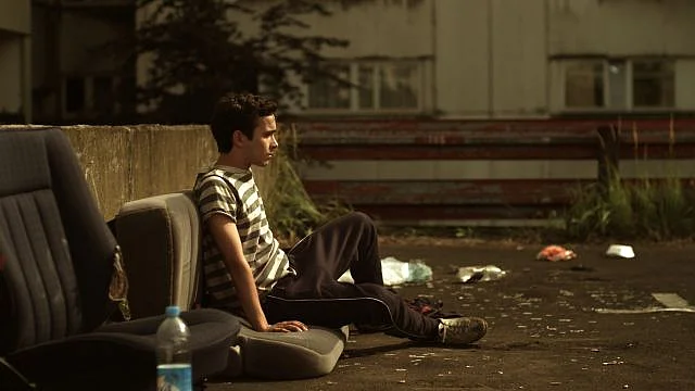 Szenenbild: Ali sitzt in einem Hinterhof auf alten Autositzen