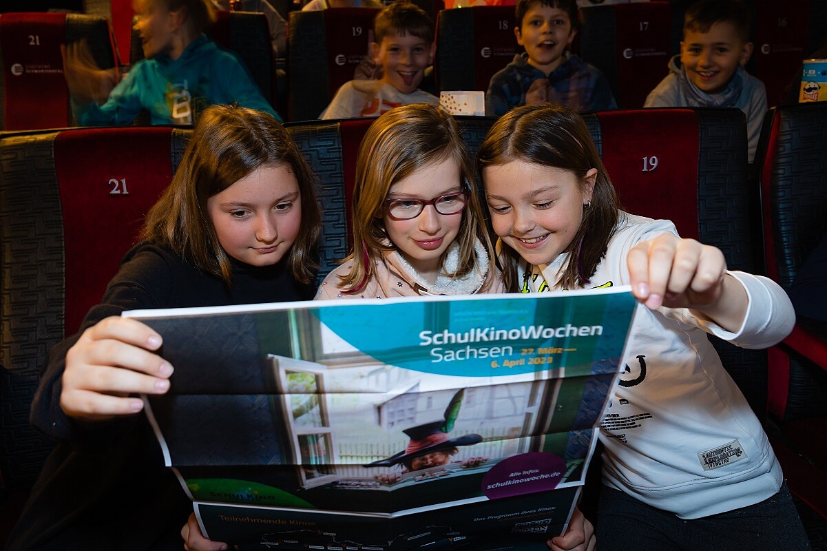 SchulKinoWochen Sachsen Drei Kinder schauen auf ein Plakat der SchulKinoWochen Sachsen