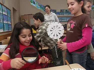 Kinder erproben ein optisches Spielzeug